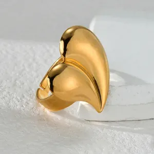 Irregular heart shaped gold stainless steel open ring on a white textured stone base