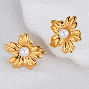 Detail of matte gold flower earrings with brushed texture and a centered white pearl
