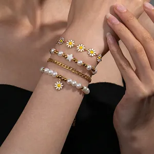 Set di quattro bracciali a strati con ciondoli a margherita, stelle dorate e perle bianche