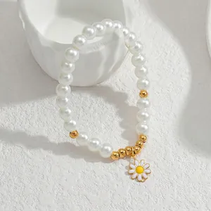 Vista macro del bracciale con ciondolo a margherita, perle bianche e perline dorate