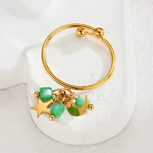 Detail of gold moon and star charms with green beads on a stainless steel bangle