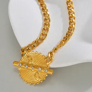 Macro detail of golden chain necklace with spiral textured pendant and five crystals