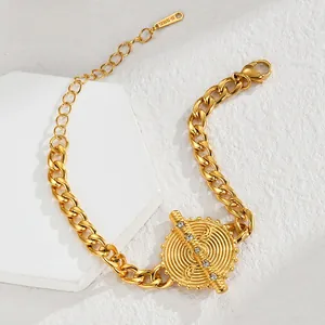 Detail of gold Cuban link bracelet with a textured disc pendant and sparkling zircons