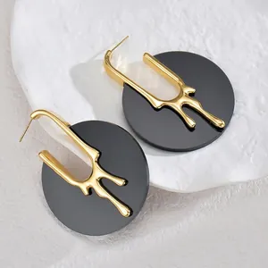 Détail de la texture de lave dorée sur des boucles d'oreilles noires rondes