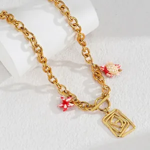 Détail d'un collier chaîne dorée avec pendentifs étoile de mer, tortue et géométrique
