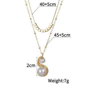 Close-up of double layer gold necklace featuring square beads and two large white pearls