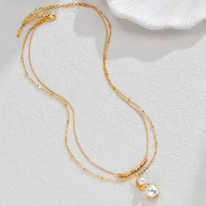 Detail of a double-layered gold pearl necklace with square beads on stone background