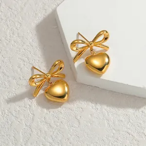 Gros plan détaillé des boucles d'oreilles dorées avec nœud et pendentif cœur poli