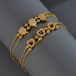 Gold double-layered snake chain bracelet with sparkling clover and heart pendants