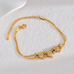 Detail of gold-plated stainless steel double-layered bracelet with clover charms and zircons