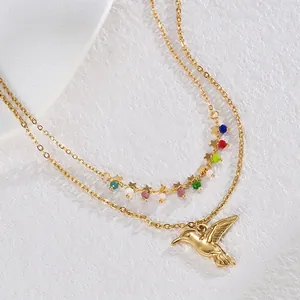Detail of double-layer gold necklace with colorful beads and small hummingbird pendant