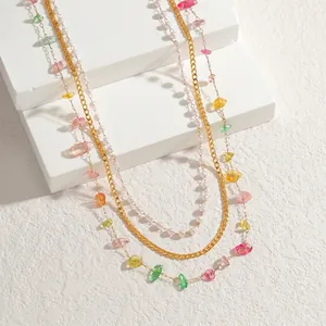 Detail of layered gold necklace with white pearls and colorful transparent crushed stones