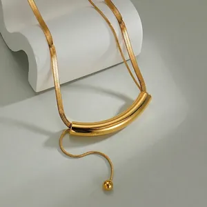Detail of 18K gold snake chain necklace with sleek curved tube and bead pendant