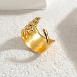 Artistic hand-shaped 18k gold-plated stainless steel open ring on a white textured stone