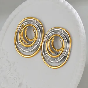 Macro detail of bi-color oval spiral earrings on a decorative white stone display plate