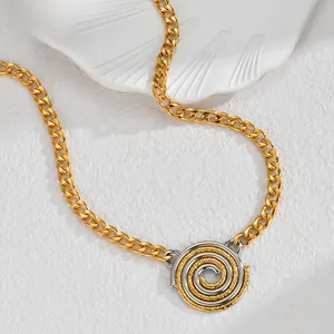 Detail shot of a two-tone spiral pendant on a gold curb chain with a sandy texture finish