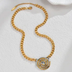 Detail of two-tone stainless steel spiral pendant with frosted texture on gold chain