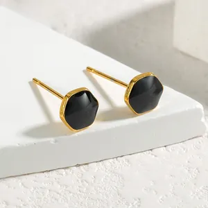 Macro shot of geometric hexagonal stud earrings with black enamel and gold metal frame