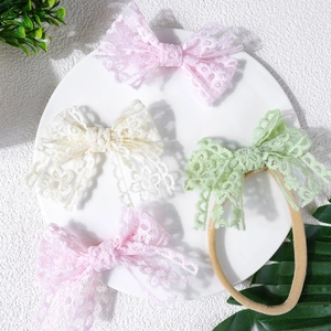 Bandeaux bébé avec nœuds en dentelle rose, beige et vert sur fond blanc épuré