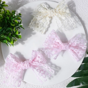 Bandeaux en dentelle pour bébés en rose et crème, présentés sur un plateau blanc pur