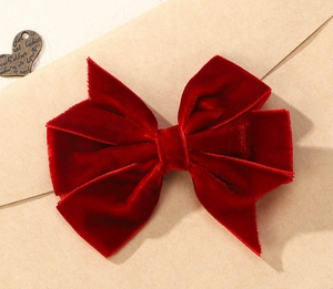 Detailed view of the dark red velvet bow hair clip with vintage heart decoration