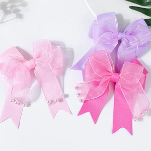 Detalle de pinzas para el pelo de organza con lazos en capas y perlas blancas