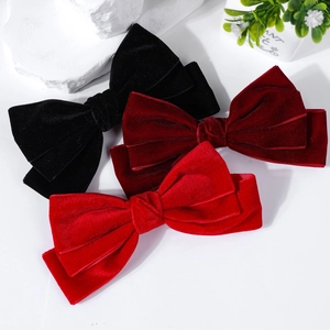 Detailed view of triple-layered velvet bow hair clips in black, burgundy, and red colors