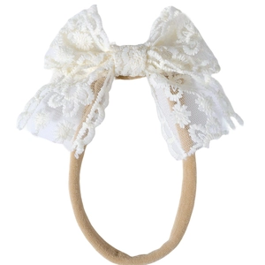 Détail du nœud en dentelle blanche et du bandeau élastique en nylon pour bébé