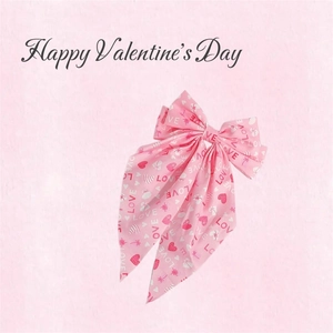 Detailed view of pink fabric hair bow with heart prints and Love text for Valentine's Day