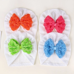 Dettaglio di quattro cappellini per neonati con grandi fiocchi a fiori in chiffon