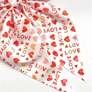 Detail of white satin hair clip with red hearts and LOVE print texture and silk finish