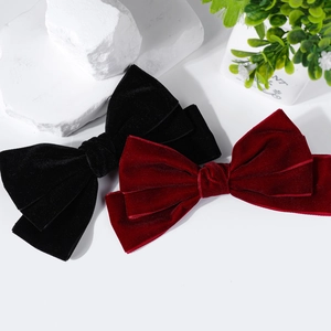 Detail view of large velvet bow hair clips in black and burgundy with textured fabric