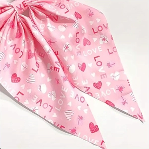 Detail of pink satin bow hair clip with LOVE text and red heart pattern print