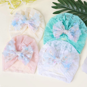 Détail de quatre bonnets en dentelle pour bébé avec grands nœuds et fleurs