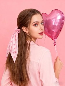 Détail d'un chouchou en satin rose avec longs rubans, cœurs rouges et imprimés LOVE
