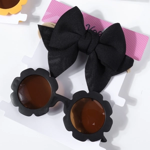 Détail d'un ensemble bébé avec bandeau noir à nœud et lunettes de soleil fleurs