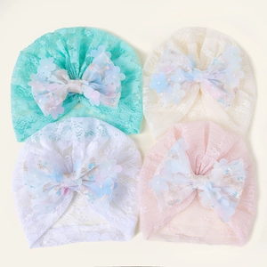 Vue à plat de quatre turbans en dentelle pour bébé avec grands nœuds et fleurs pailletées