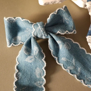 Nahaufnahme der blauen Denim-Schleife mit weißer Spitze und zartem Blumenmuster