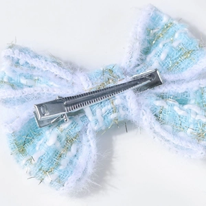 Détail de la pince à cheveux en tweed montrant le clip en métal argenté et bordure