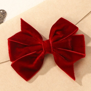Elegant deep red velvet bow hair clip with layered vintage texture on paper background