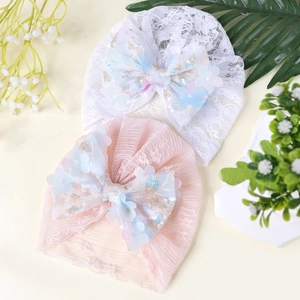 Gros plan de bonnets en dentelle pour bébé avec nœuds en résille et fleurs pailletées