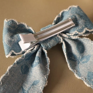 Nahaufnahme der Entenschnabelklemme auf Vintage-Denim-Schleife mit weißer Spitze