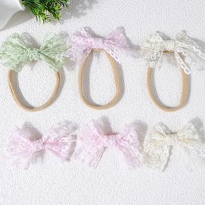 Détail de bandeaux bébé en dentelle avec nœuds en vert, rose et beige pour filles