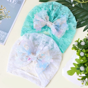 Détail du turban en dentelle pour bébé avec paillettes et grand nœud sur tissu doux