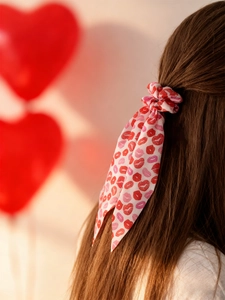 Détail d'un chouchou blanc avec imprimés lèvres et longs rubans sur cheveux bruns