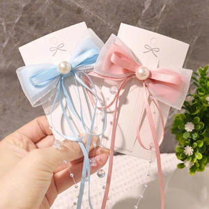 Detailansicht der rosa und blauen Schleifen-Haarspangen mit Satinband und Perlen