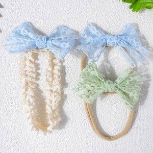 Détail du lot de bandeaux et élastiques en dentelle pour bébé sur surface texturée blanche