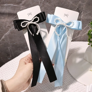 Nahaufnahme von schwarzen und hellblauen Satin-Haarspangen mit eleganten Perlenverzierungen