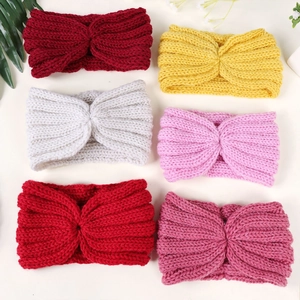 Flat lay detail showing six colors of knotted knitted headbands with warm wool texture