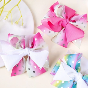 Detail of three colorful gradient bow hair clips with silver heart patterns for girls